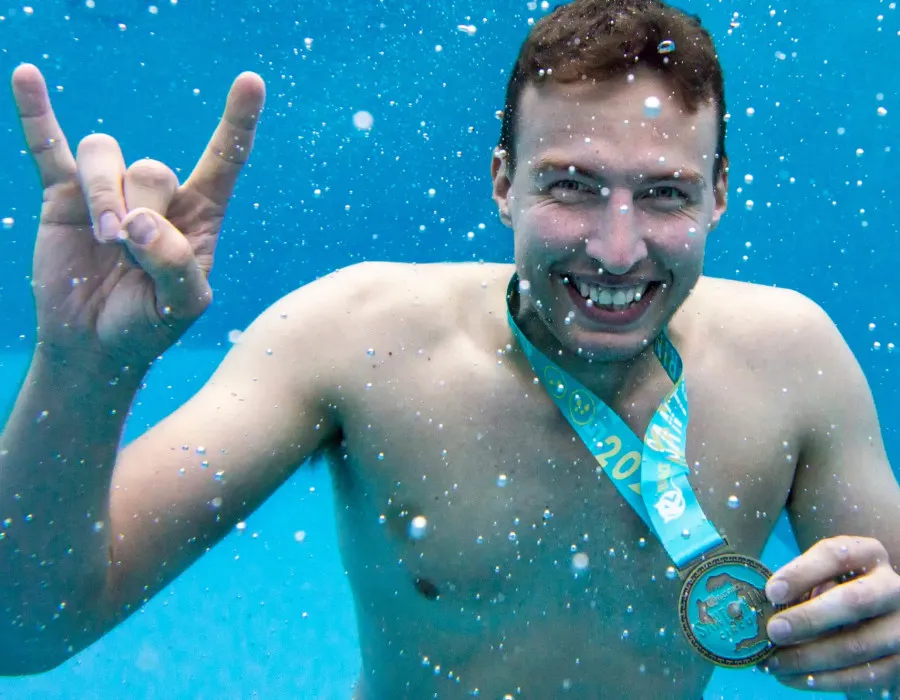 Man underwater, wearing Santorini medal