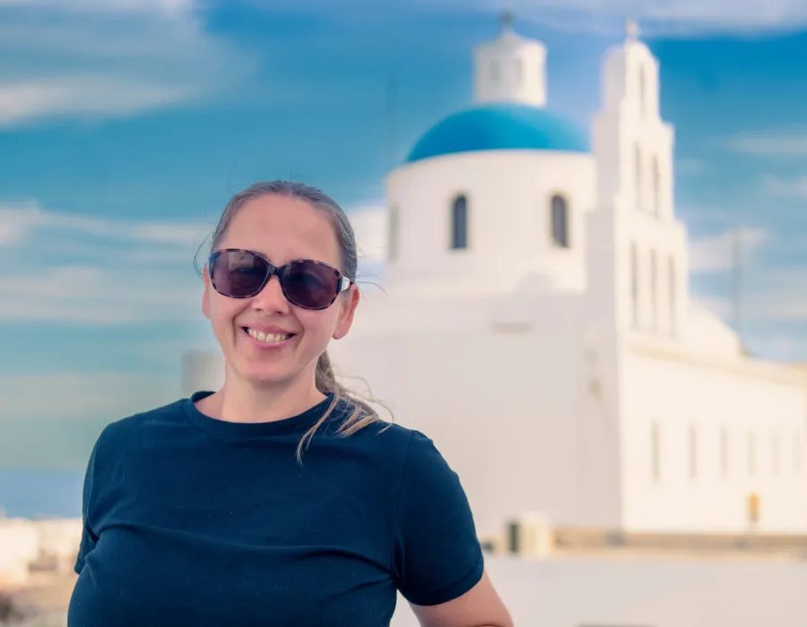 Woman smiling and stood infront of white and blue building