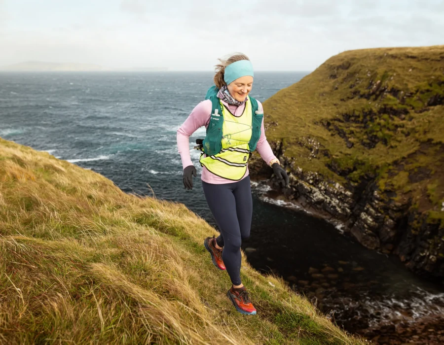 Woman running along grassy coastline