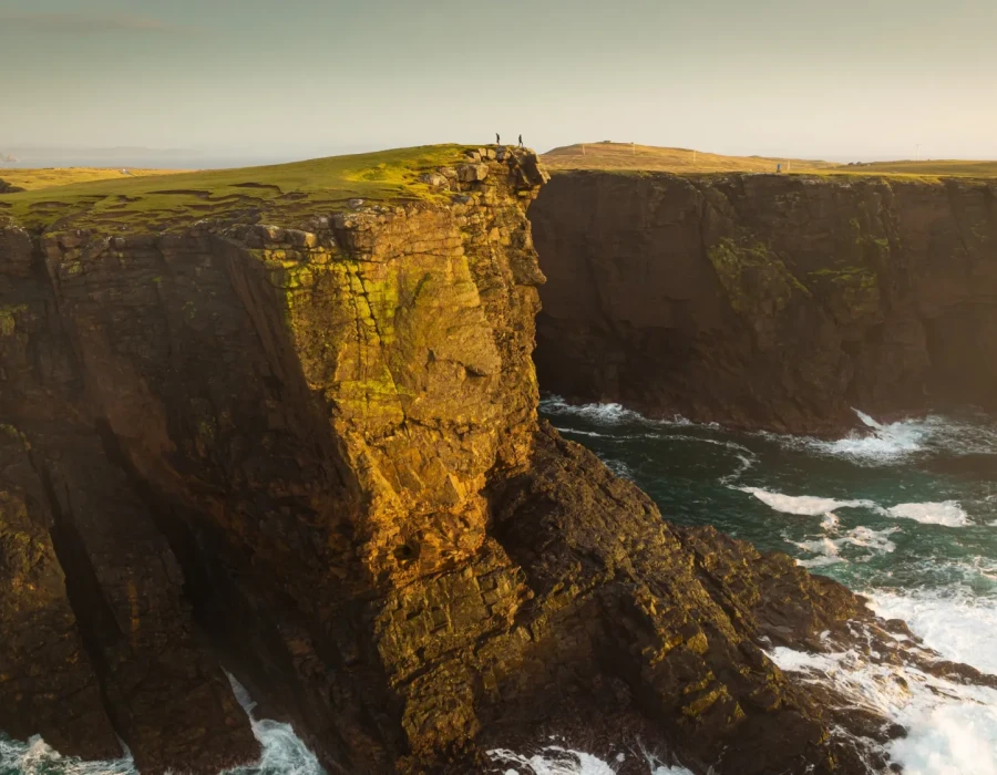Sunlit cliff and crashing sea below