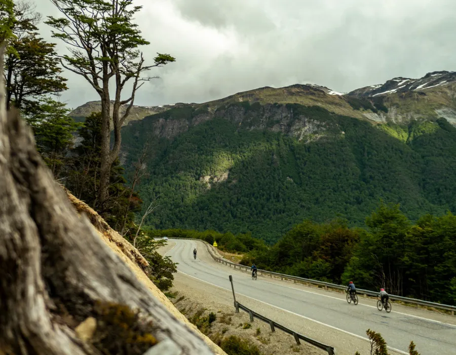 Cyclists travelling along road surrounded by mountains and greenery