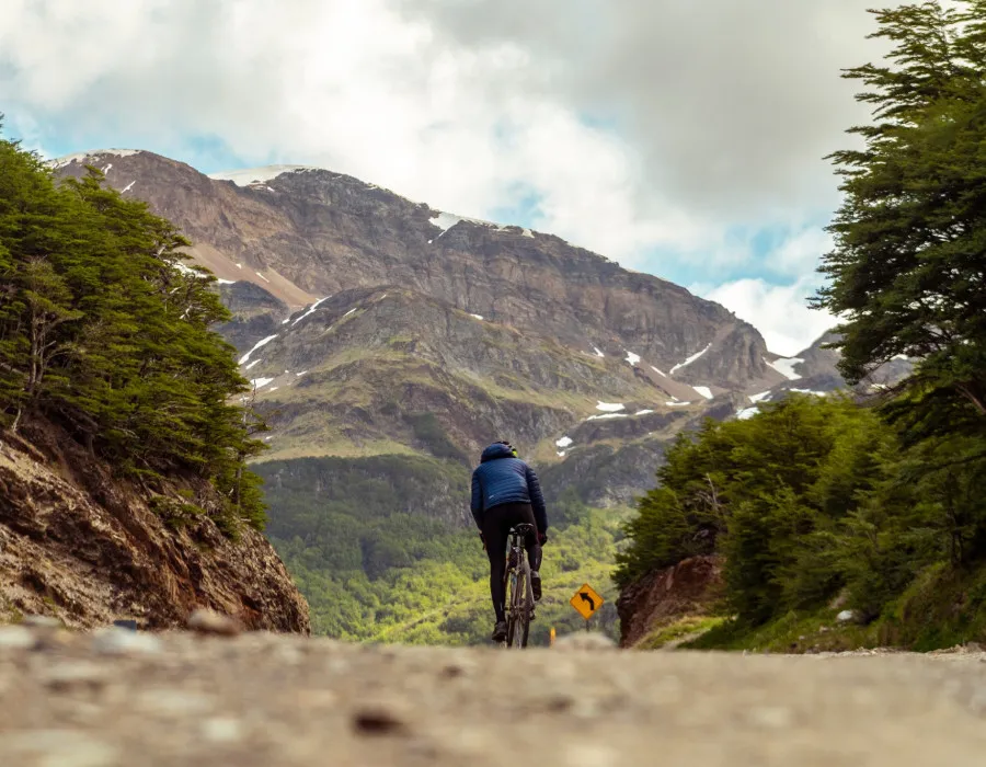 Cyclist riding along road, towards mountains
