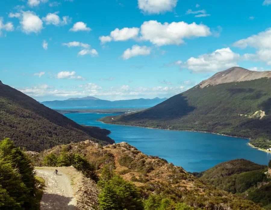 Cyclist riding along rocky path next to water and mountains