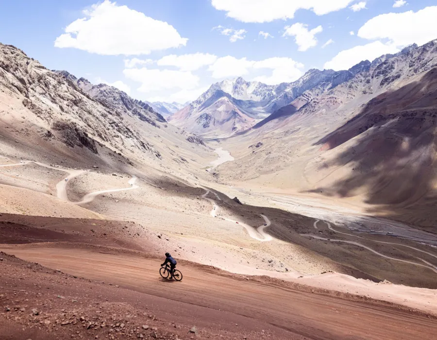 Cyclist riding along rocky path next to mountains