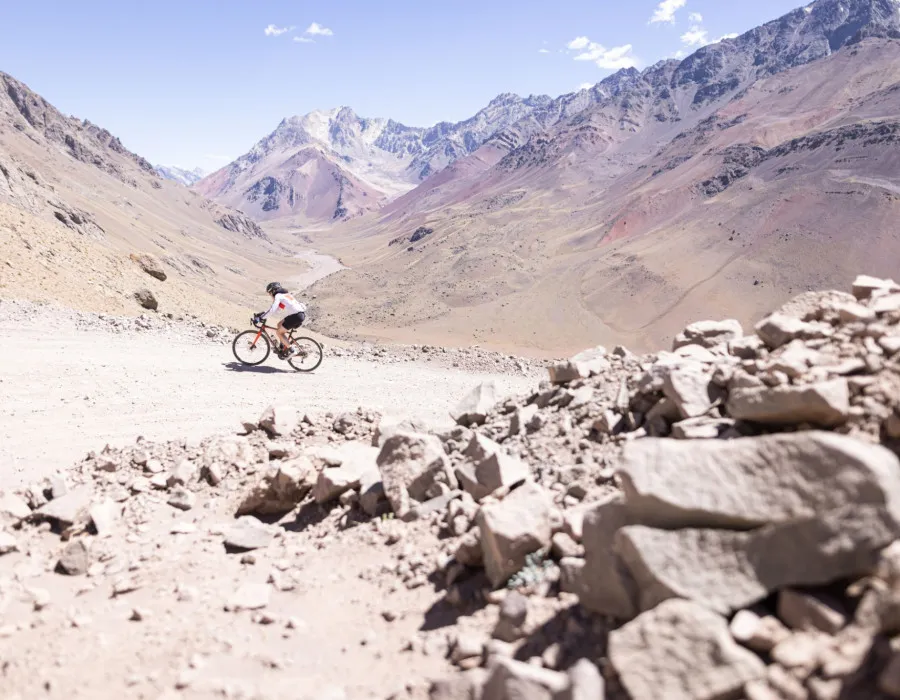 Cyclist riding along dusty terrain surrounded by mountains