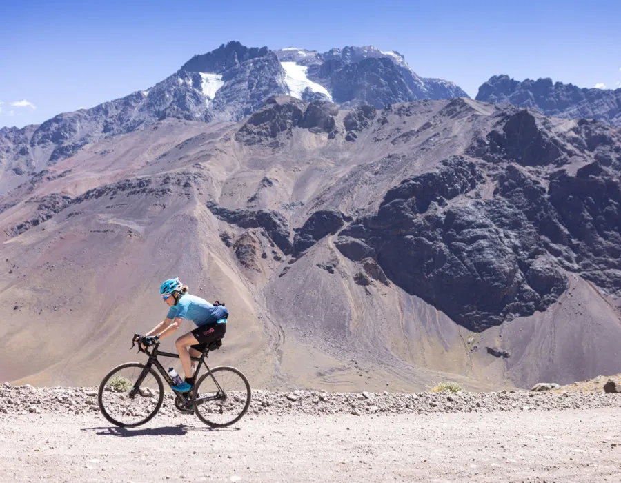 Cyclist riding along rocky path next to mountains