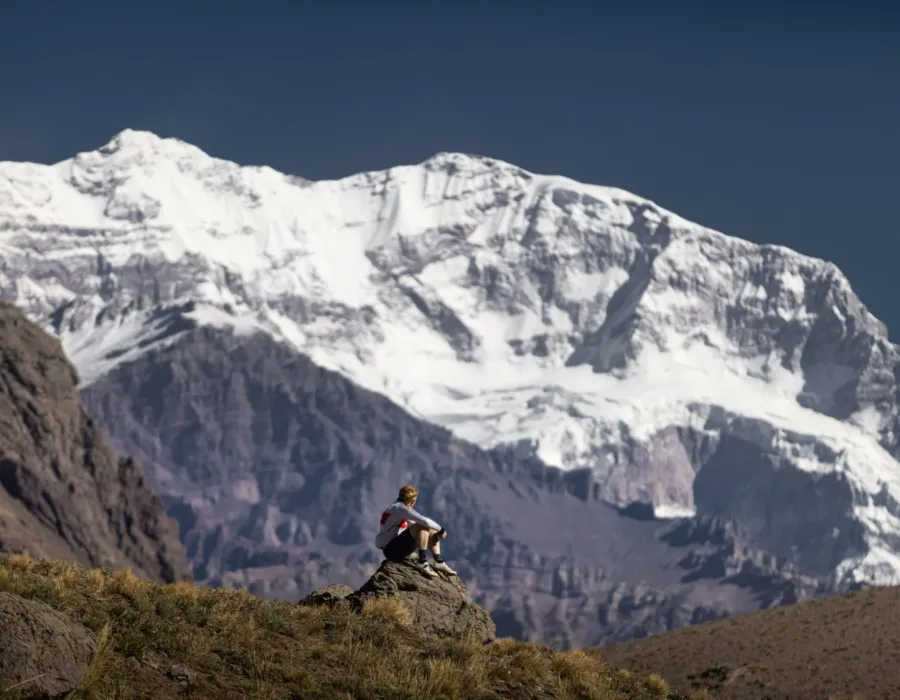 Participant sat on rock, looking up at snow-covered mountain