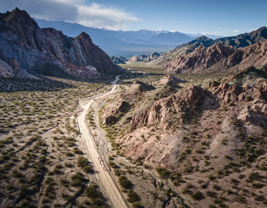 Cyclists riding along road, surrounded by mountains and sparse greenery