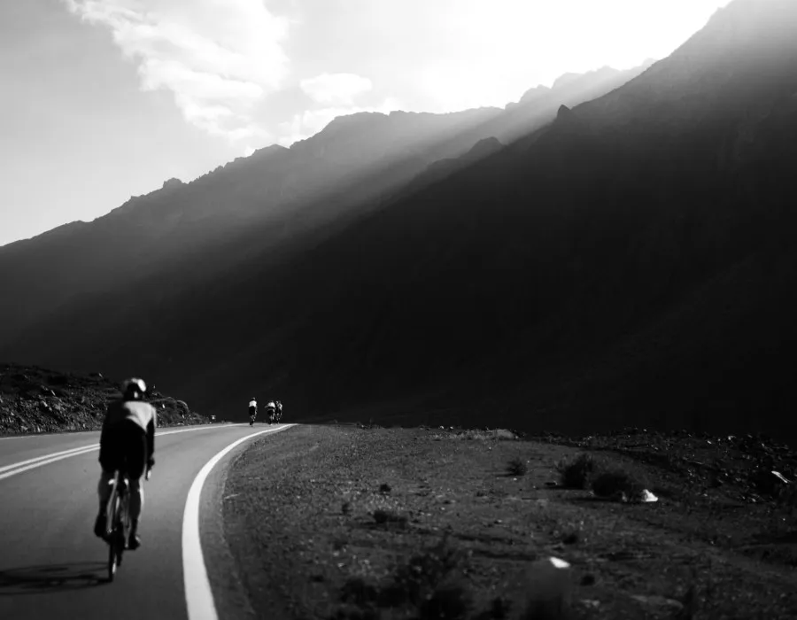 Dark image of cyclists riding past mountains