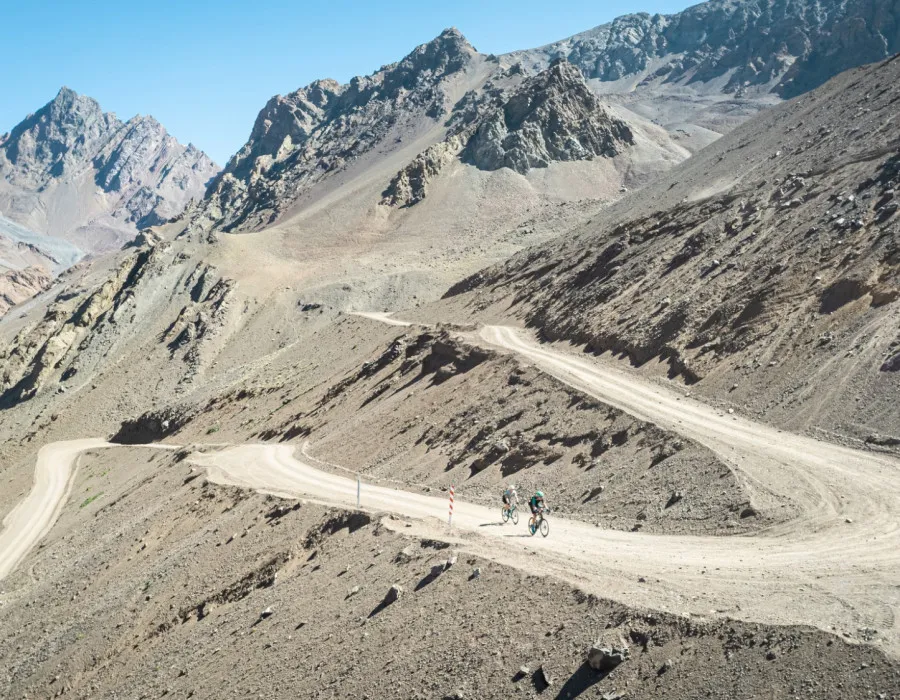 Cyclists riding along winding road up mountains