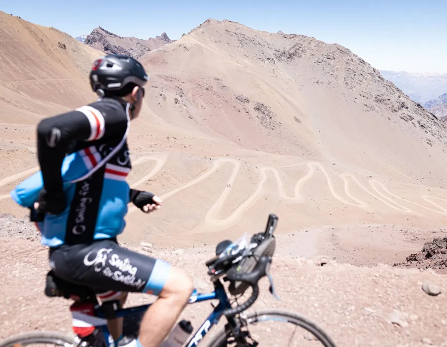 Cyclist looking at winding path and mountain