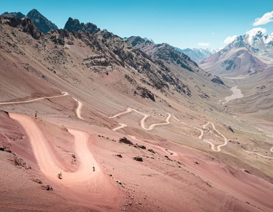 Winding road on dusty terrain with mountains behind