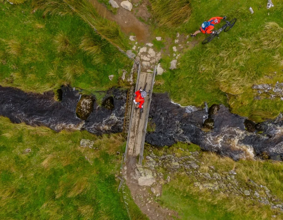 Aerial view of cyclists crossing bridge over running water