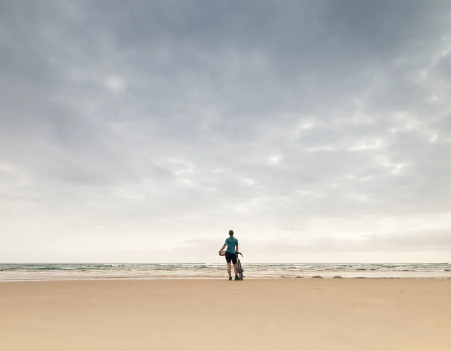 Woman standing on sandy beach with bike