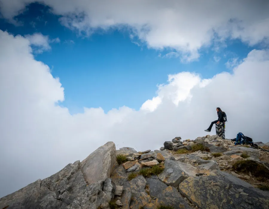 Woman sat on rocky terrain with blue sky and clouds above