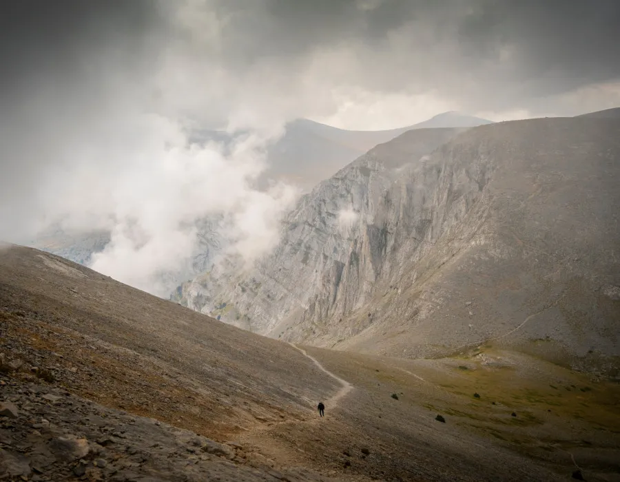 Person walking on rocky terrain with mountain behind