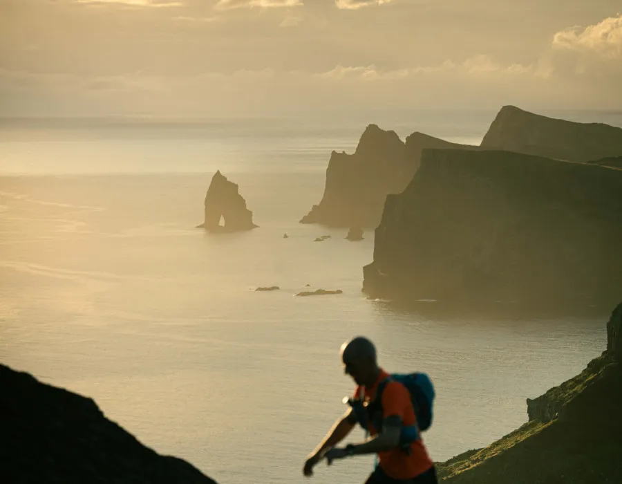 Man running up hill with sea and islands behind