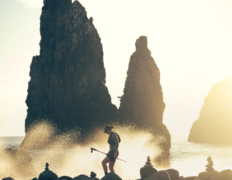 Participants running over round rocks and sea crashing against them