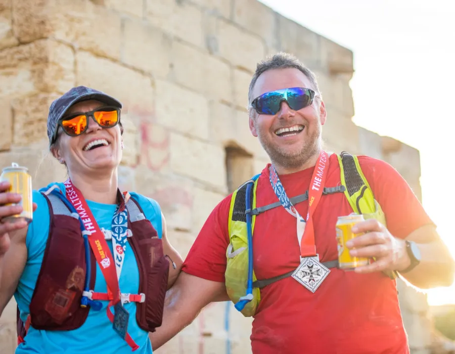 Man and woman holding canned drinks and smiling in the sunshine
