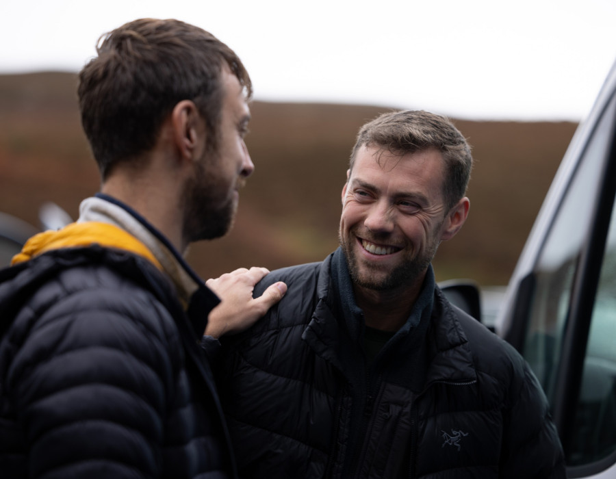 Two men smiling as one put his hand on the other's shoulder