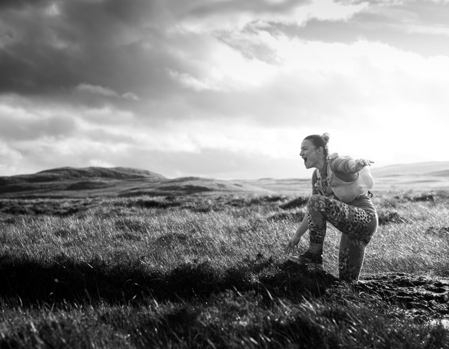 Woman climbing on grassy, rocky terrain