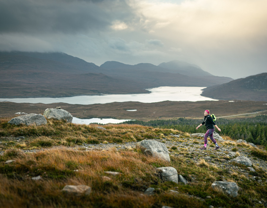 Woman walking on rocky, grass terrain