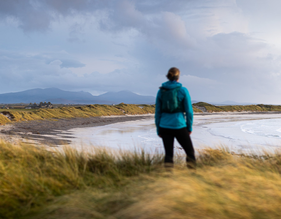 Woman stood on grass, looking out at water