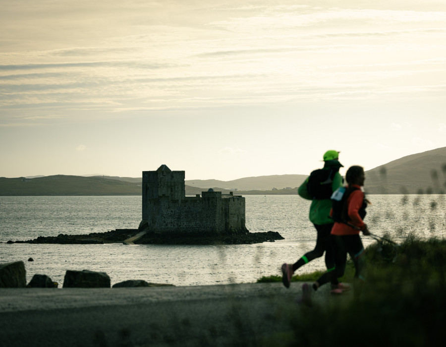Two people running on road alongside water