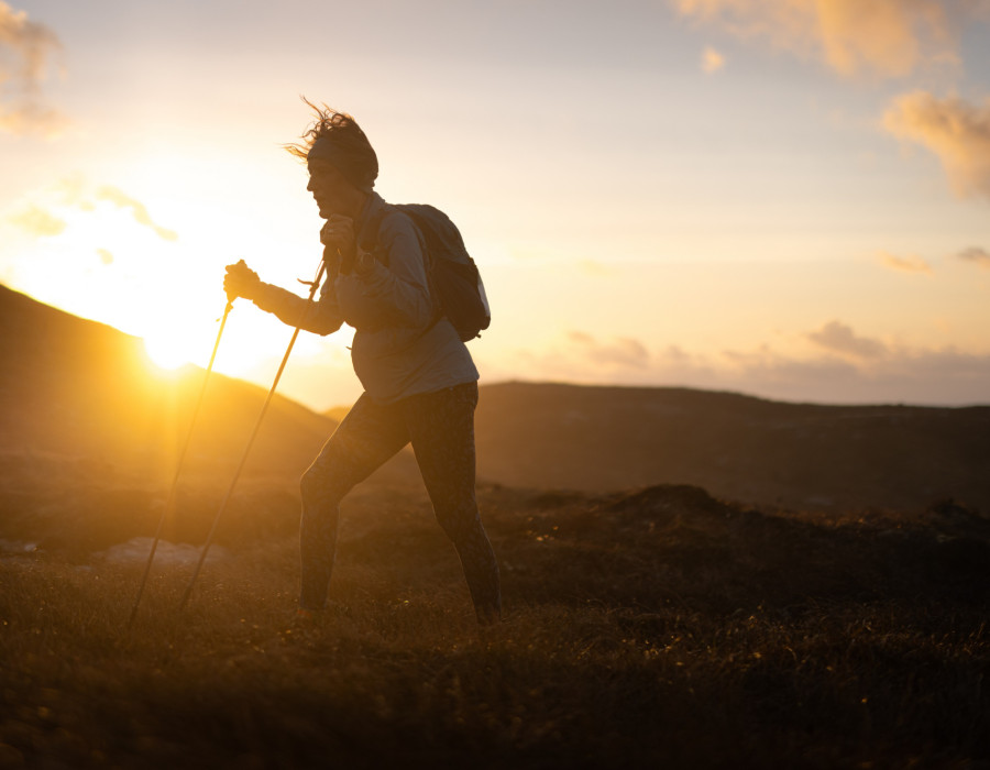 Woman hiking on grass at sunset