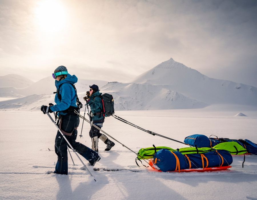 Two participants pulling sleds through snow