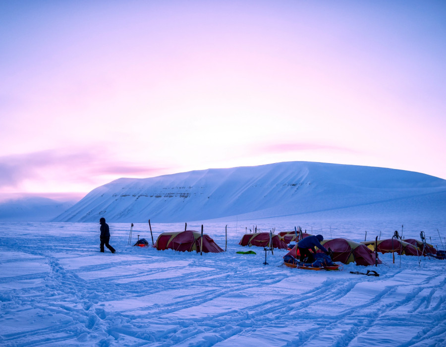 Participant walking away from tents pitched in deep snow