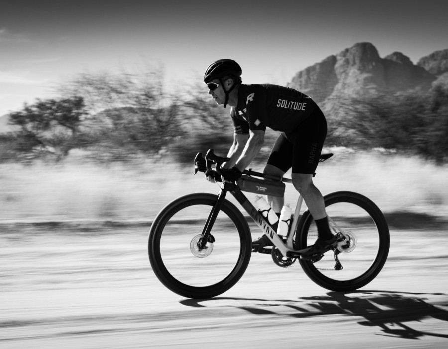 Cyclist riding along at speed with trees in background