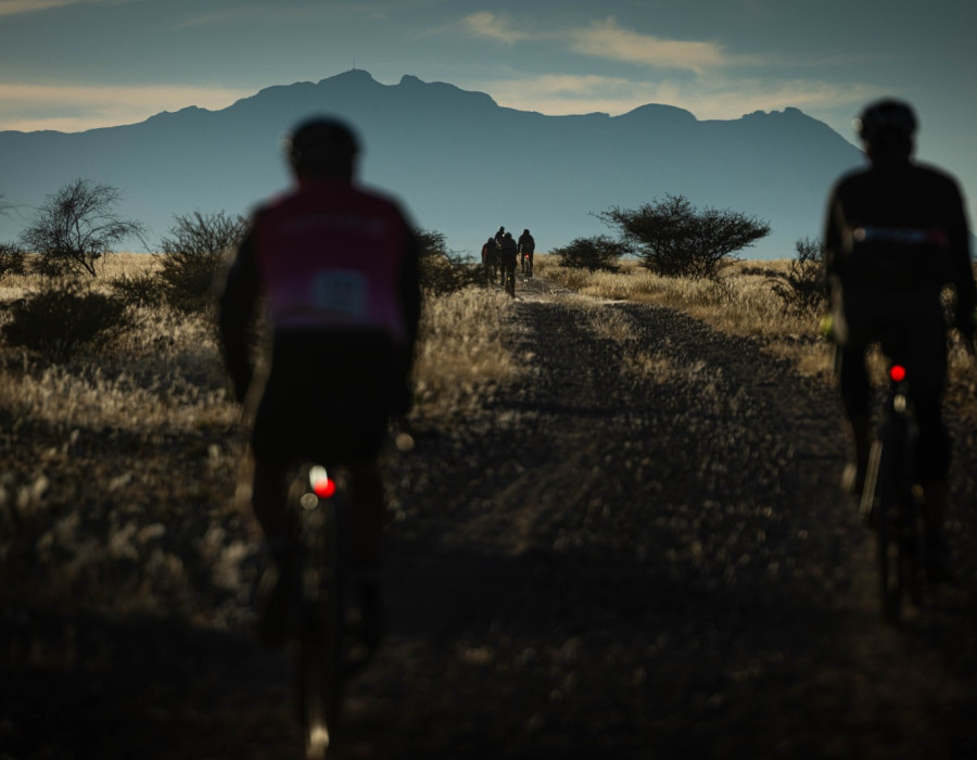Cyclists riding along track with mountains ahead