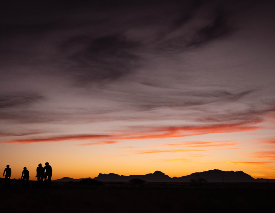Silhouettes of cyclists with dark, colourful sky behind
