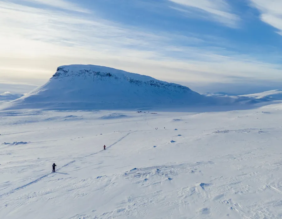 Participants crossing a winter, snowy landscape