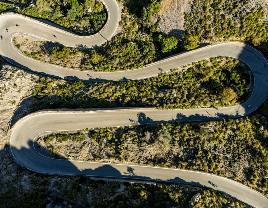 A winding road snaking through a rocky terrain dotted with sparse trees