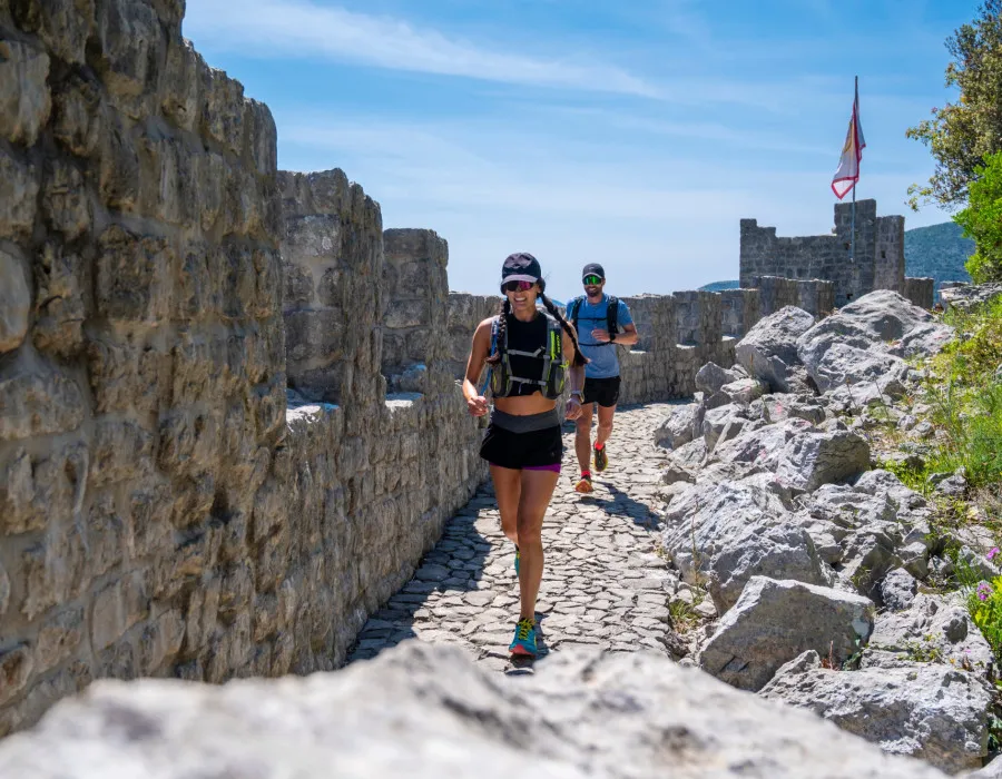 A man and a woman run next to a wall