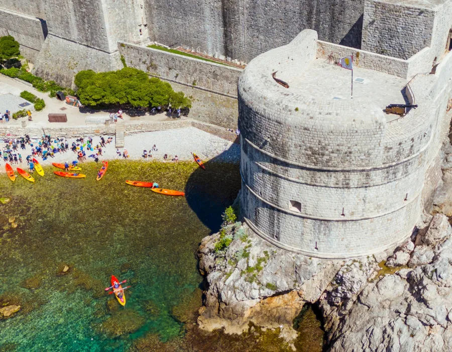 Group of people beginning their kayak on shallow, turquoise water, next to a wall