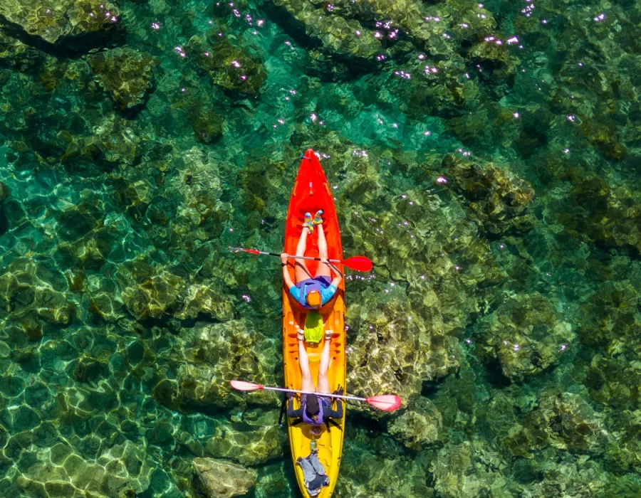 An aerial view of two participants kayaking through clear water