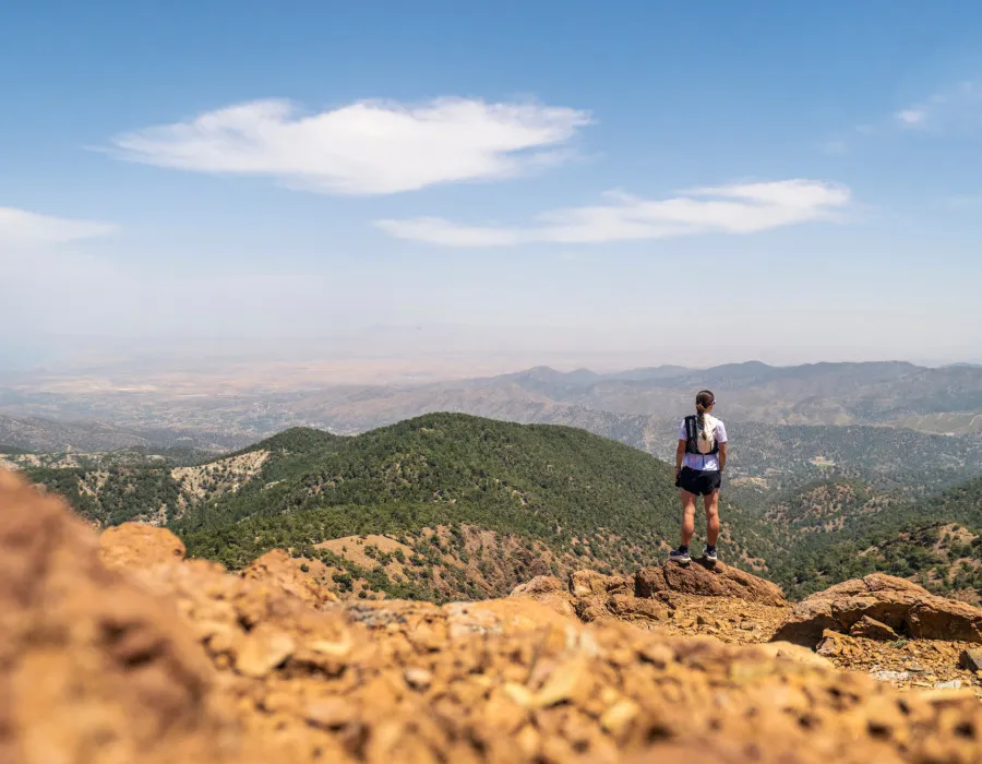 Woman looking out onto rolling mountains, with sparse greenery