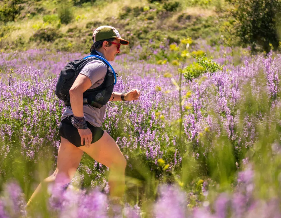 Participant running through greenery and colourful flowers