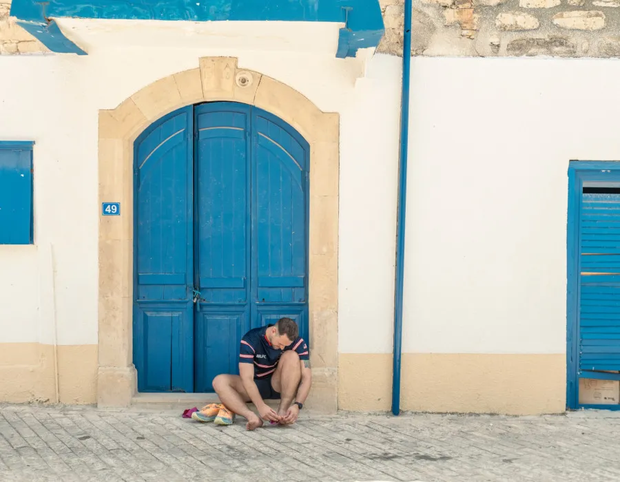 Man sat on a doorstep, with a large blue door behind him