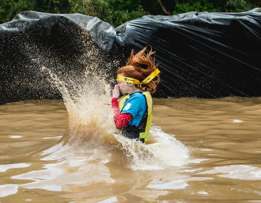 Woman, wearing colourful clothing and jumping into dirty water