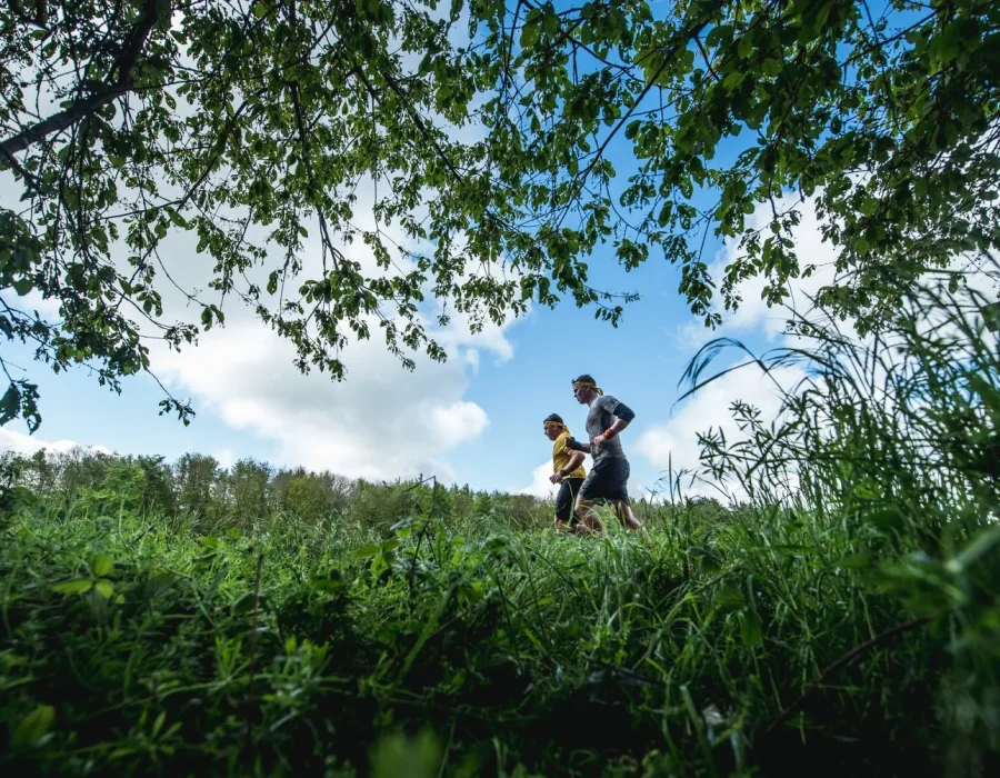 Men running through grassland, with trees hanging over them