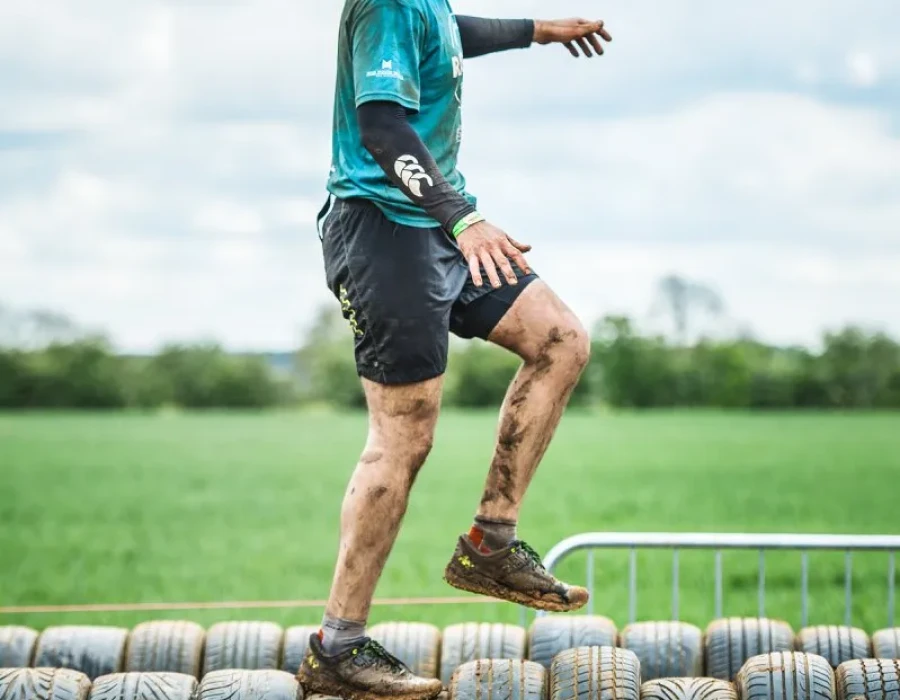 Mud-covered man walking along tyres