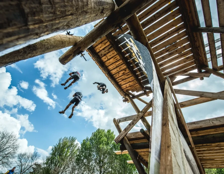 Participants jumping from a wooden ledge, with bright, blue sky above them