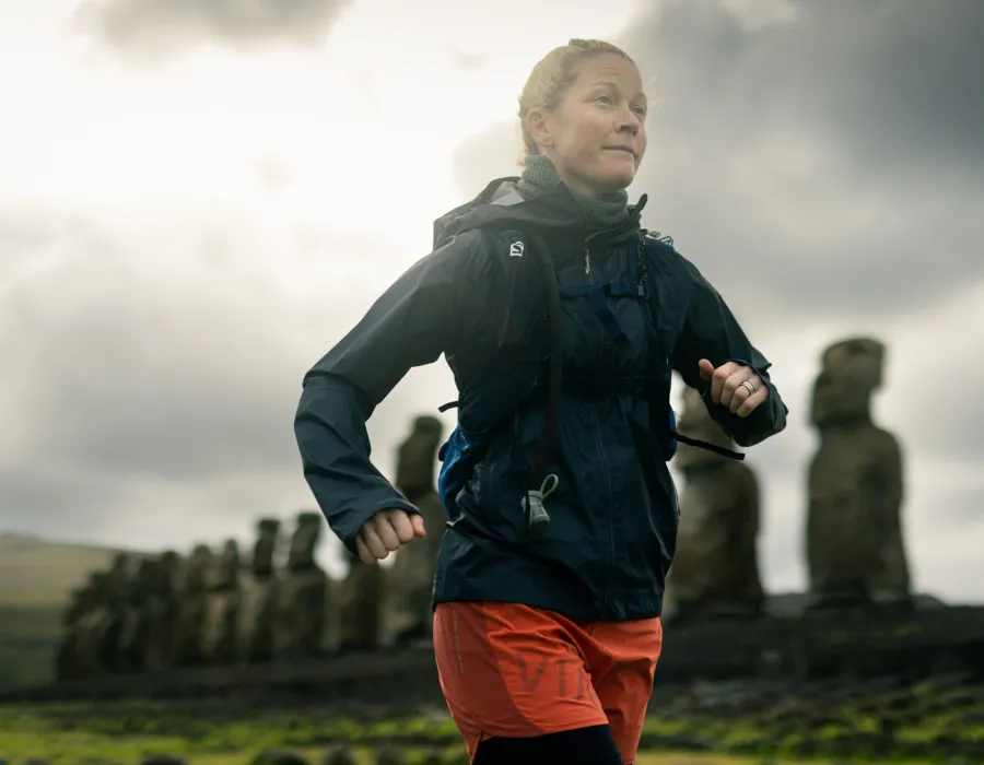 Woman running past a wall of statues