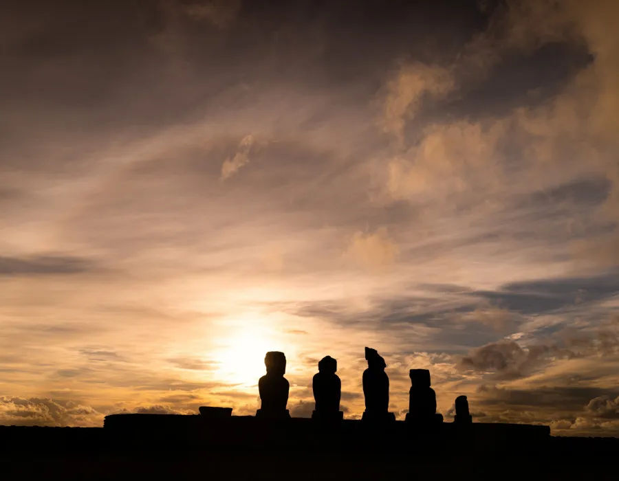 Silhouettes of statues and a colourful sky behind them