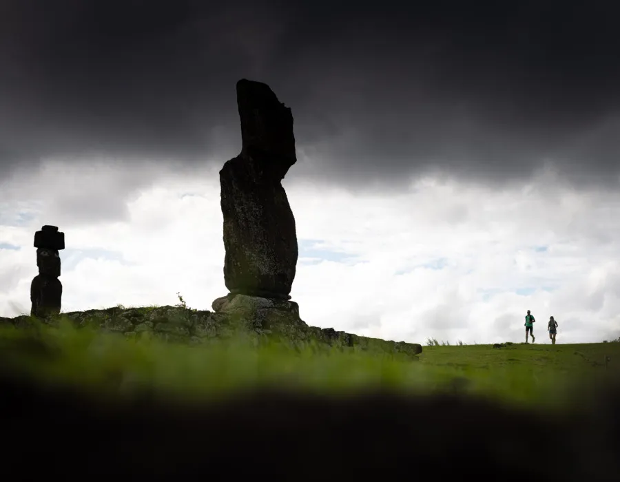 Participants running past large statues with a dark sky above them