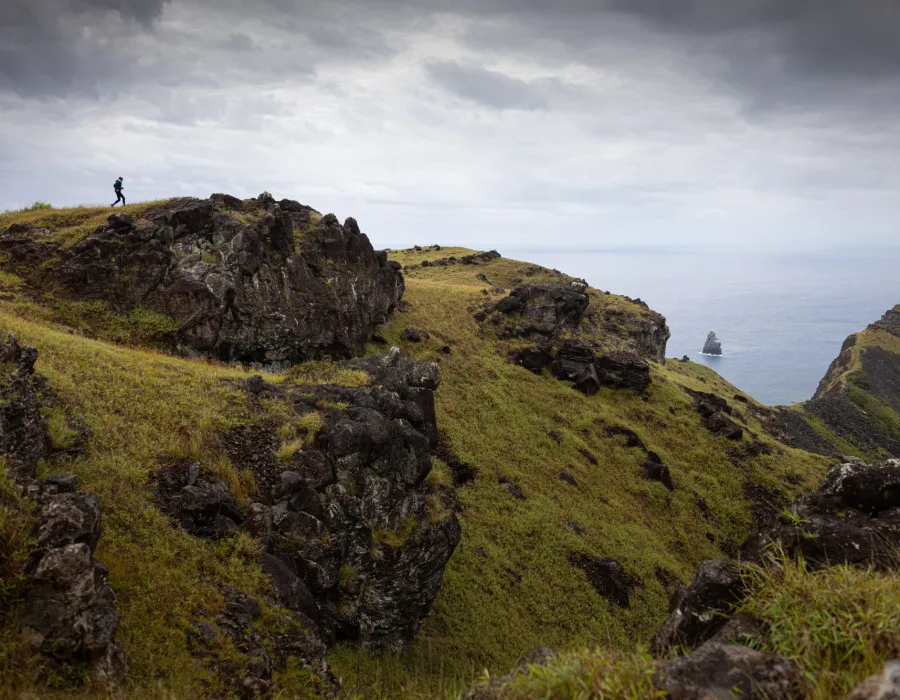 Man running over rocky hills covered in grass